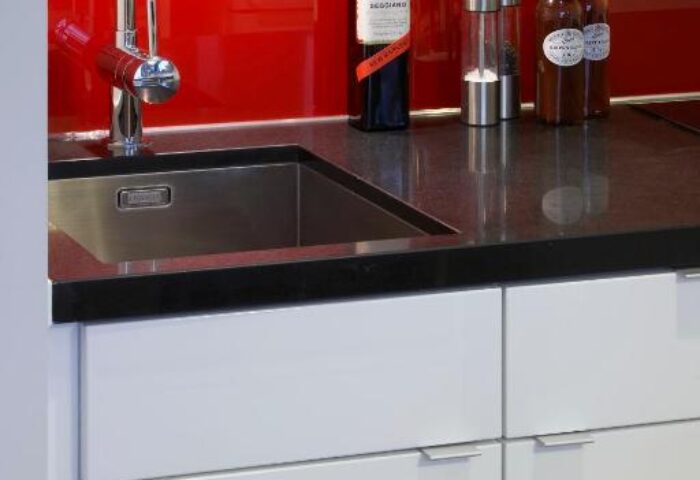 Citadines Holborn-Convent Garden London kitchen detail. Sink, red backsplash, & condiments on counter. Gay-friendly hotel apartment living.