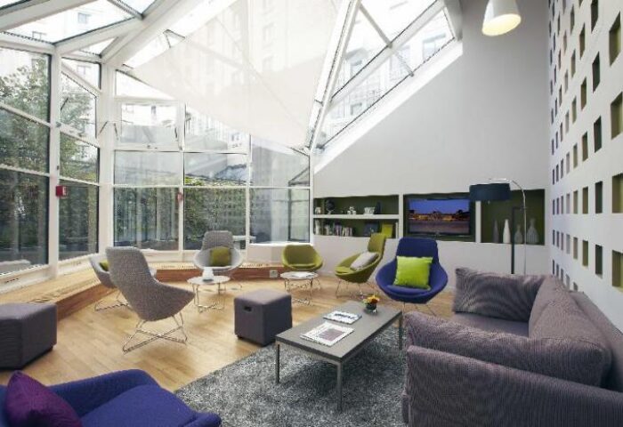 Citadines Les Halles Paris's bright lounge. Gay-friendly, pet-friendly hotel with modern decor, skylight, and comfortable seating. Ideal Paris stay.
