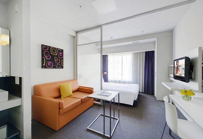 Citadines Shinjuku Hotel room. Gay-friendly hotel with a bed, sofa, desk, and TV. Modern design for a comfortable stay in Tokyo, Japan.