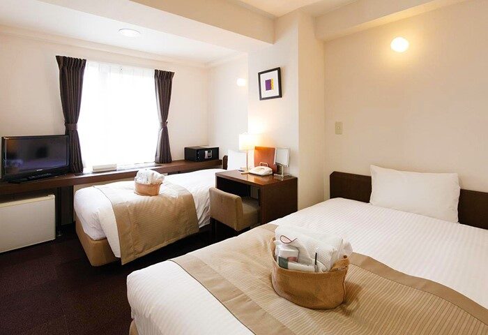 City Hotel Lonestar gay-friendly room with two beds, desk, TV, safe. Comfortable stay for gay travelers.