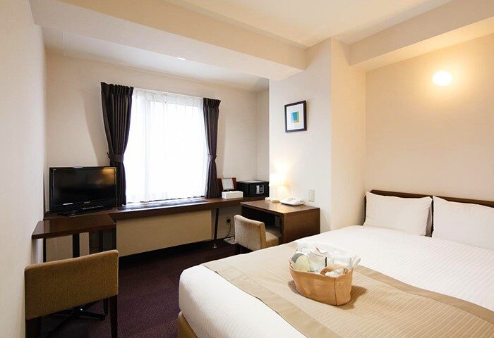 City Hotel Lonestar room. Gay-friendly hotel with a bed, desk, TV, and window. A basket of amenities sits on the bed. Modern, clean design.