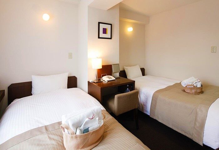 City Hotel Lonestar gay-friendly room with twin beds, desk, lamp, and towels. A comfortable stay for gay travelers.