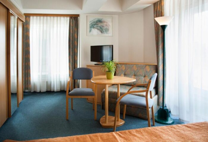 City Hotel Matyas room interior. Gay-friendly hotel with table, chairs, TV, and sofa. A comfortable space for gay travelers in Budapest.