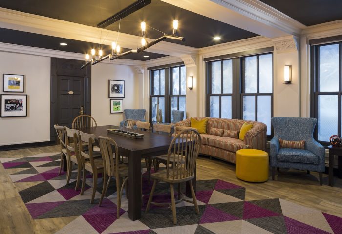 City Suites Chicago gay-friendly hotel lounge area. Long table, chairs, sofa, and armchairs create a welcoming space. Geometric rug adds flair.