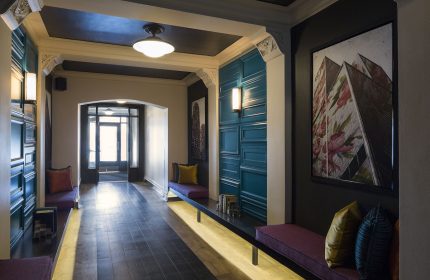 City Suites Chicago gay-friendly hotel interior. Hallway with benches, artwork, and decorative wall panels. Modern design elements.
