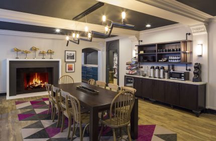 City Suites Chicago gay-friendly hotel dining area with fireplace, long table, chairs, and coffee bar. Modern design elements.