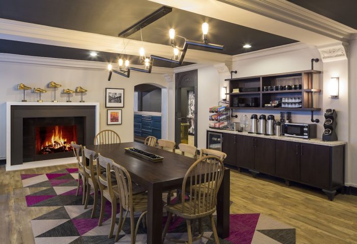 City Suites Chicago gay-friendly hotel dining area with fireplace, long table, chairs, and coffee bar. Modern design elements.