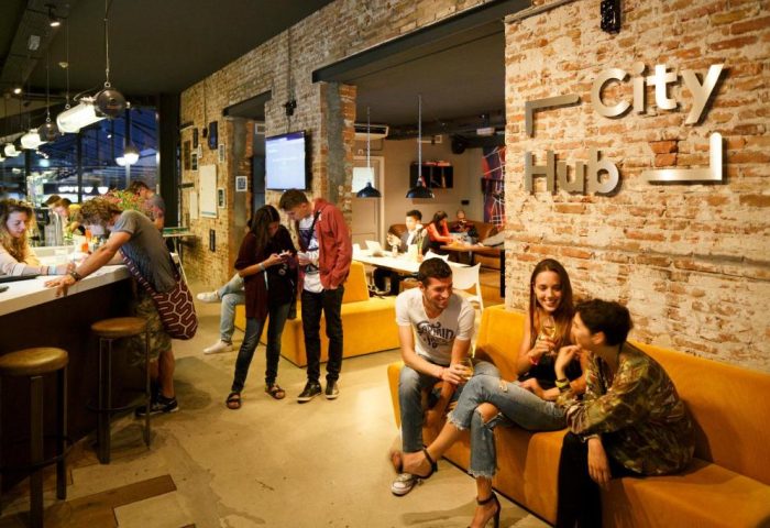 CityHub Amsterdam interior. Guests socialize in the hip, gay-friendly hotel's common area with exposed brick and modern design.