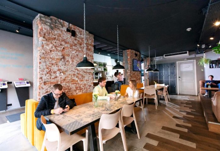 CityHub Amsterdam's interior: Guests at tables, exposed brick, modern design. A gay-friendly hotel with a stylish, welcoming atmosphere.