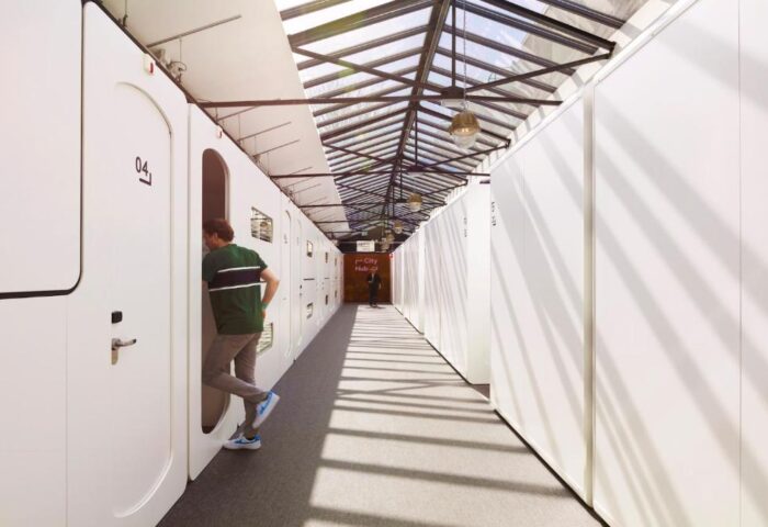 CityHub Amsterdam interior. A gay-friendly hotel with modern pod-style rooms. Man entering a pod. Skylight above. Unique Amsterdam stay.