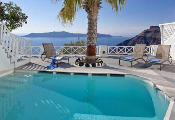 Cliff Side Suites gay-friendly hotel pool. Ocean view, lounge chairs, and palm tree. Perfect for gay travel and relaxation. Santorini suites.