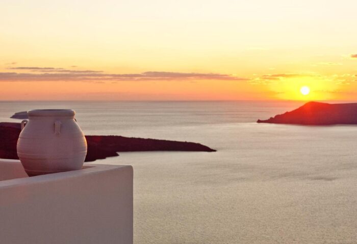 Sunset view from Gay-Friendly Cliff Side Suites. Ocean view with islands, vase on a ledge. A perfect gay travel destination for relaxation.