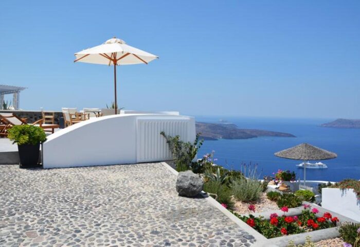 Gay-Friendly Cliff Side Suites. Outdoor patio with sun umbrella, stone walkway, and ocean view. A gay travel destination for a relaxing vacation.