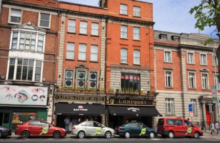 Clifton Court Hotel, a gay-friendly hotel in Dublin, Ireland. Red brick building with taxis parked outside. Gay travel destination.