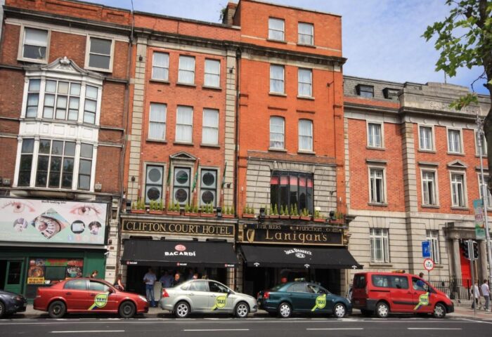 Clifton Court Hotel, a gay-friendly hotel in Dublin, Ireland. Red brick building with taxis parked outside. Gay travel destination.