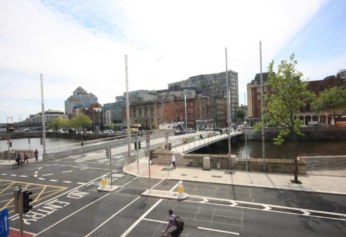 Dublin street view from Clifton Court Hotel, a gay-friendly hotel. A cyclist rides on the road near the river and bridge.