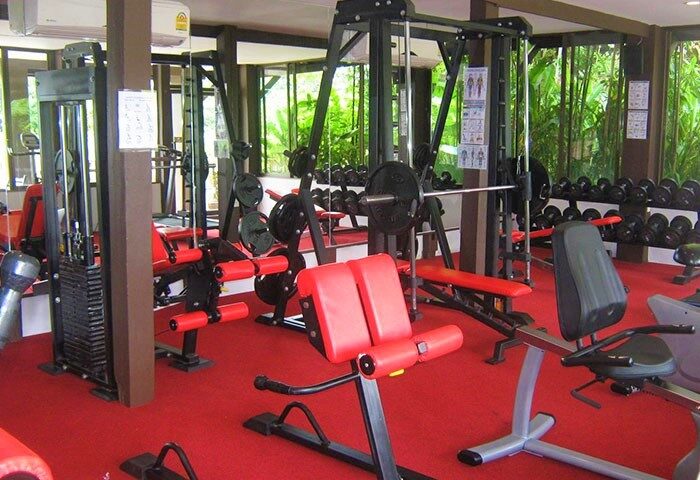 Gym at Club One Seven Gay Men Hotel, Chiang Mai. Weight machines, dumbbells, and red carpet. Gay-friendly hotel fitness center.