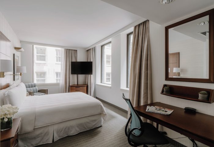 Club Quarters Hotel, Central Loop bedroom. Gay-friendly hotel room with bed, desk, TV, and windows. Modern, clean design.