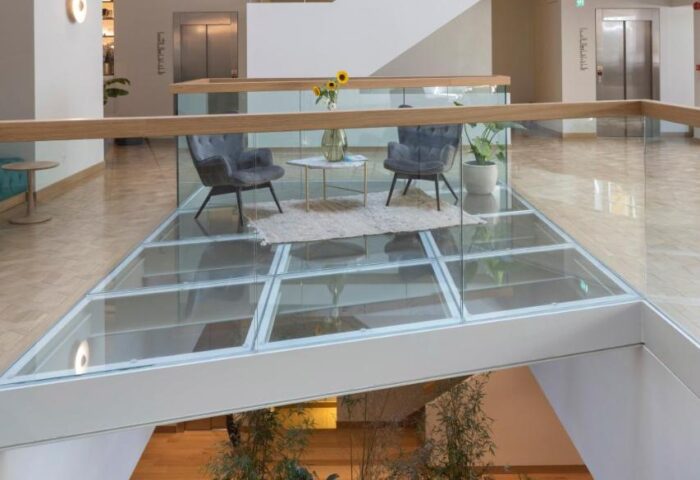 Coco-mat Athens BC gay-friendly hotel interior. Modern design with glass floor, seating area, and indoor plants. Stylish, welcoming space.