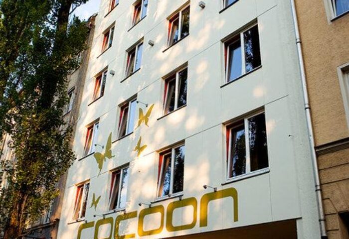 Cocoon Sendlinger Tor hotel exterior. Gay-friendly hotel in Munich, Germany. Modern building with cocoon logo and butterfly design.