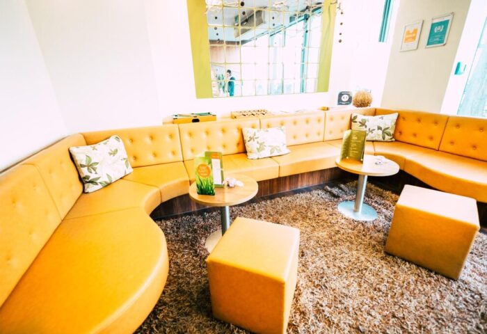 Cocoon Sendlinger Tor gay-friendly hotel: Stylish seating area with orange couches, tables, and ottomans. Modern design for gay travelers.