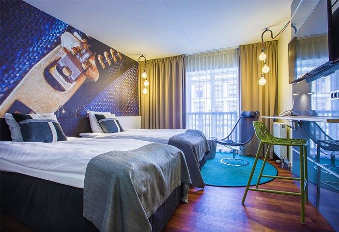 Comfort Hotel Vesterbro room. Gay-friendly hotel with two beds, a zipper mural, chair, and desk. Modern design in Copenhagen.