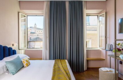 Condominio Monti Boutique Hotel bedroom. Gay-friendly hotel room with open windows, blue headboard, and view of Rome. Great for gay travelers.