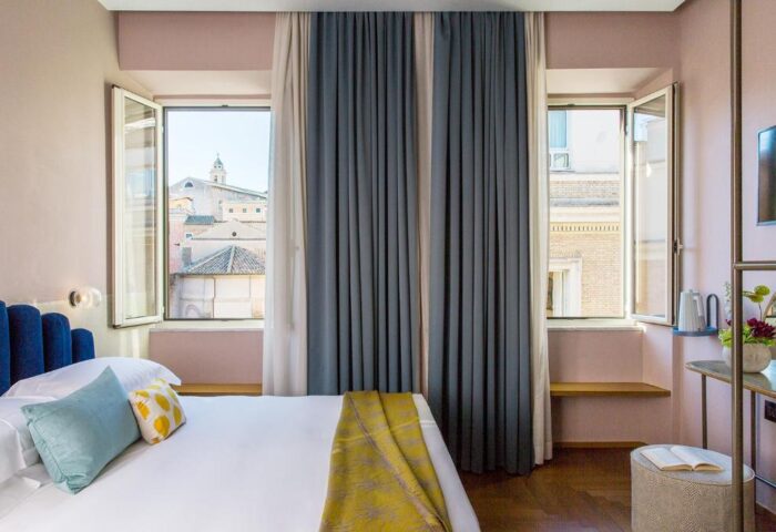Condominio Monti Boutique Hotel bedroom. Gay-friendly hotel room with open windows, blue headboard, and view of Rome. Great for gay travelers.