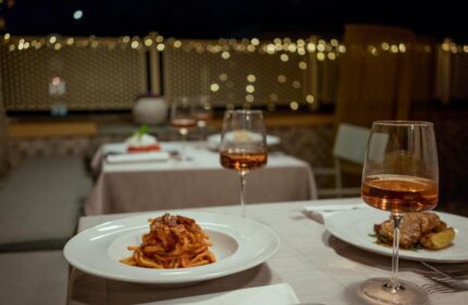 Fine dining at Condominio Monti Boutique Hotel, a gay-friendly hotel. Pasta dish and wine glasses on a beautifully set table. Romantic ambiance.