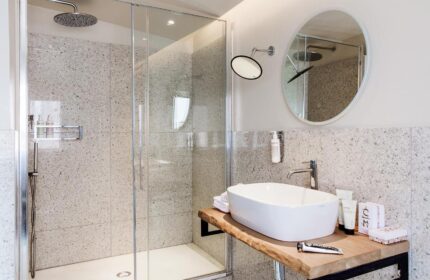 Condominio Monti Boutique Hotel gay-friendly bathroom. Features walk-in shower, modern sink, and round mirror. Stylish design for gay travelers.