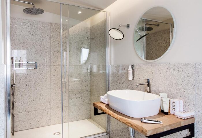 Condominio Monti Boutique Hotel gay-friendly bathroom. Features walk-in shower, modern sink, and round mirror. Stylish design for gay travelers.
