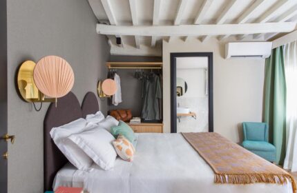 Condominio Monti Boutique Hotel gay-friendly room. Bedroom with double bed, wardrobe, design lamps, and bathroom view. Rome gay travel.