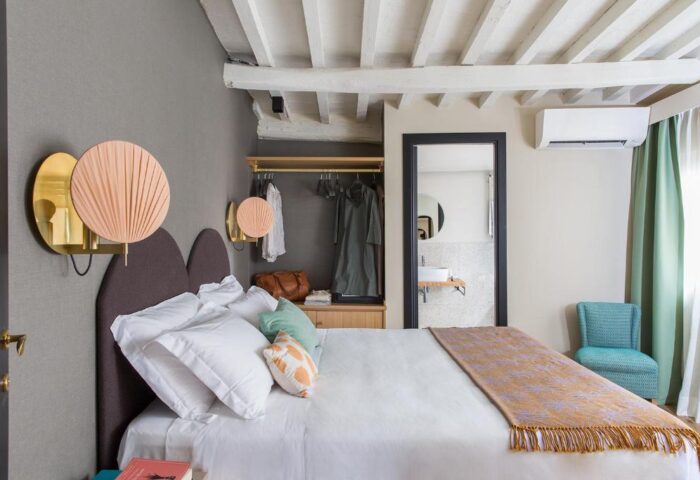 Condominio Monti Boutique Hotel gay-friendly room. Bedroom with double bed, wardrobe, design lamps, and bathroom view. Rome gay travel.