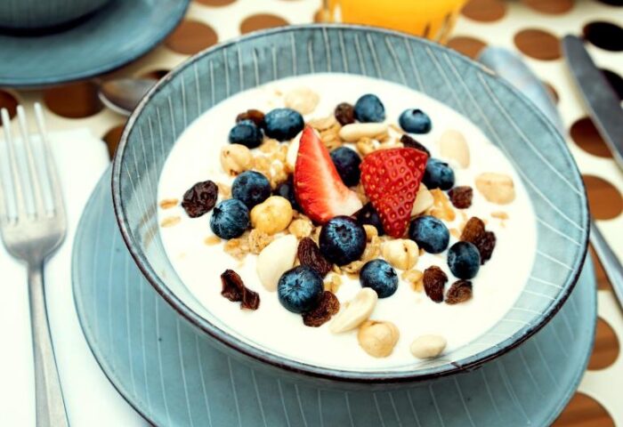 Breakfast at Condominio Monti Boutique Hotel, a gay-friendly hotel. Yogurt bowl with blueberries, strawberries, nuts, and juice.