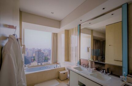 Bathroom at Conrad Beijing, gay-friendly hotel. Bathtub by window with city view. Double sinks, mirror, robes. Luxury travel for gay men.