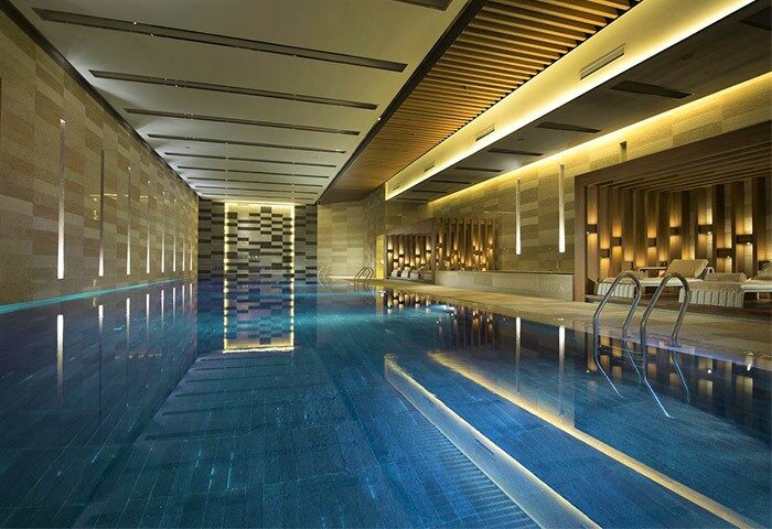 Conrad Beijing gay-friendly hotel's indoor pool. Relaxing, modern design with lounge chairs, perfect for gay men travelers in Beijing.