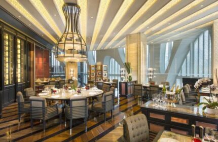 Conrad Beijing gay-friendly hotel restaurant. Dining area with modern decor, tables set for service. Upscale ambiance, perfect for gay travelers.