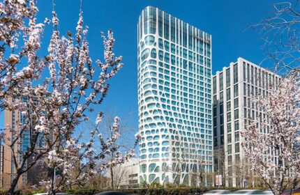 Conrad Beijing, a gay-friendly hotel. Exterior view of the modern hotel architecture with cherry blossoms in spring. Beijing travel for gay men.