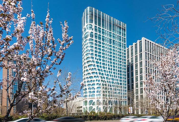 Conrad Beijing, a gay-friendly hotel. Exterior view of the modern hotel architecture with cherry blossoms in spring. Beijing travel for gay men.