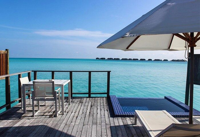 Conrad Maldives Rangali Island Resort deck with pool. Gay-friendly hotel with ocean view, table, chairs, and umbrella for gay men's travel.