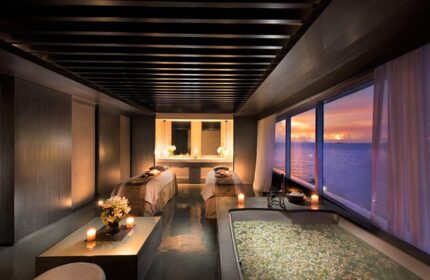 Gay-Friendly Hotel Conrad Manila spa room. Two massage beds, a flower-filled tub, and ocean sunset views. Relaxing travel experience.
