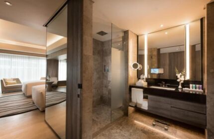 Conrad Manila gay-friendly hotel room. Modern bathroom with glass shower, large mirror, and sleek vanity. Luxurious accommodations for gay travelers.