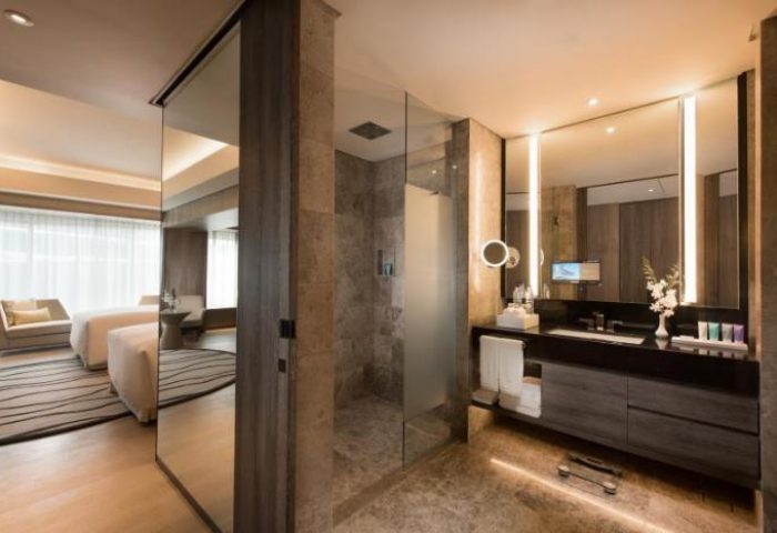 Conrad Manila gay-friendly hotel room. Modern bathroom with glass shower, large mirror, and sleek vanity. Luxurious accommodations for gay travelers.