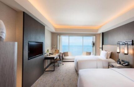 Gay-friendly Hotel Conrad Manila room. Two beds, desk, TV, and ocean view. Modern design, comfortable for gay travelers. Manila hotel room.