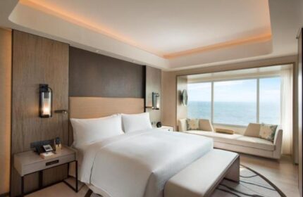 Conrad Manila gay-friendly hotel room. Modern design, king bed, ocean view, and seating area. Perfect for gay travelers seeking luxury in Manila.