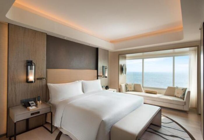 Conrad Manila gay-friendly hotel room. Modern design, king bed, ocean view, and seating area. Perfect for gay travelers seeking luxury in Manila.