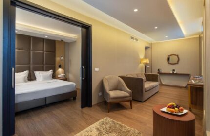 Continental Hotel: Luxurious suite with a bed, sofa, chair, and fruit plate. Gay-friendly hotel room offers comfort and style for discerning travelers.