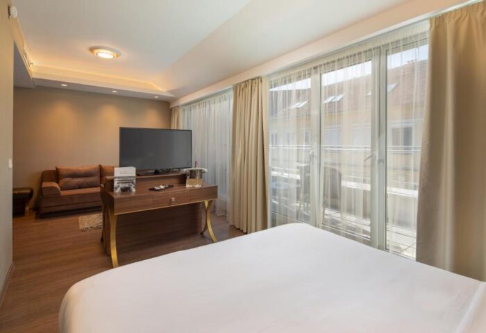 Continental Hotel room: bed, TV, and balcony. Gay-friendly hotel with modern design. Perfect for gay men's travel. Comfortable stay.