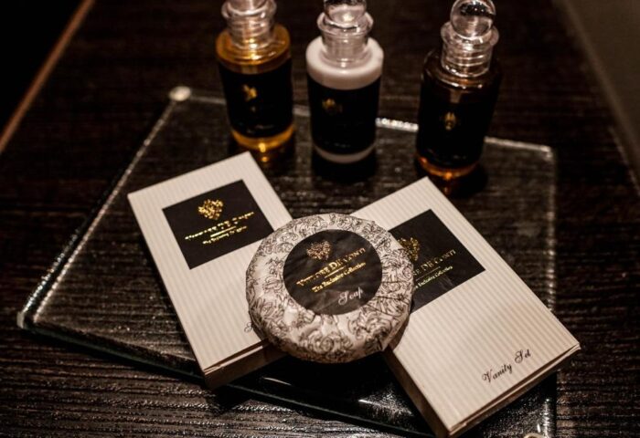 Continental Hotel's toiletries: Soap, vanity set, shampoo, and lotion on a glass tray. Gay-friendly hotel amenities detail.
