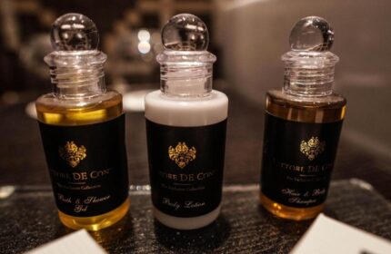 Continental Hotel toiletries. Bath gel, body lotion, and shampoo bottles on a tray. Gay-friendly hotel amenities for a comfortable stay.